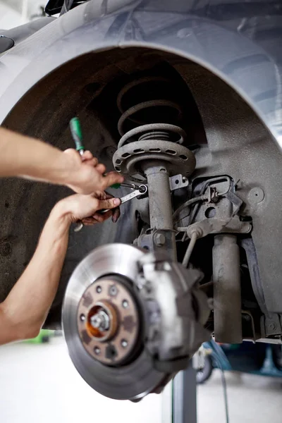 Un mécanicien non identifié réparant les plaquettes de frein avec des outils — Photo