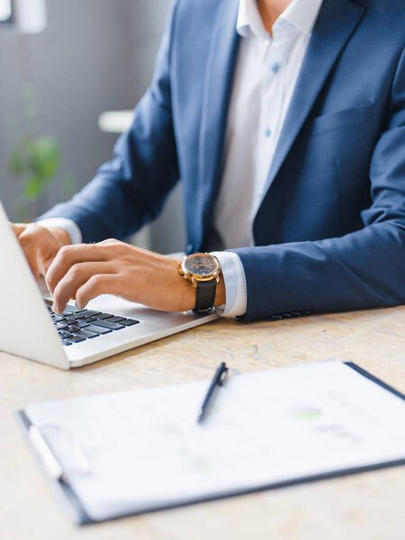 Close-up mans hands working on a wireless laptop on a blurred background. Digital design concept.