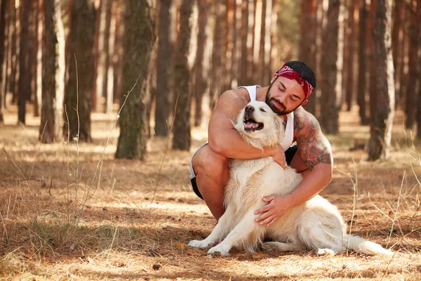 Handsome young man with a labrador outdoors in the forest. — Stock Photo, Image