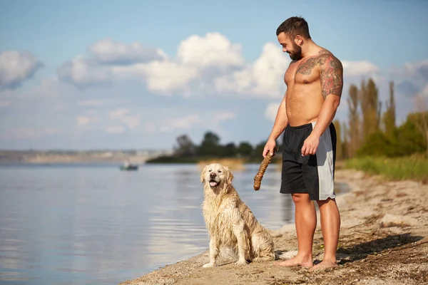Mutlu labrador zevk sahibi ile sahilde oynarken.