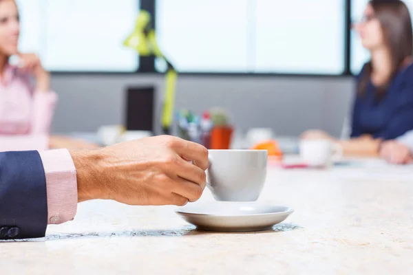 Το χέρι των εργαζομένων κατέχει ένα φλιτζάνι καφέ στο τραπέζι — Φωτογραφία Αρχείου
