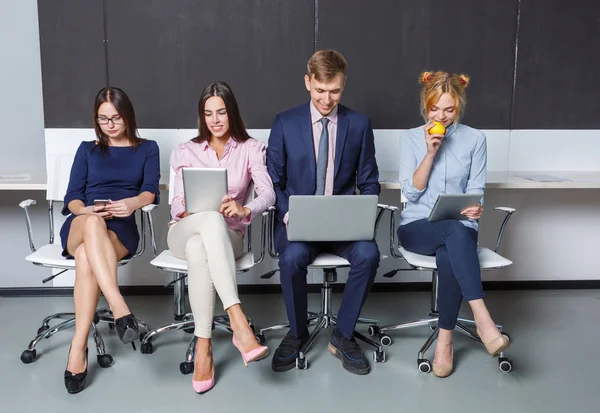 Groep van kantoorpersoneel werkt op laptops zitten op stoelen — Stockfoto