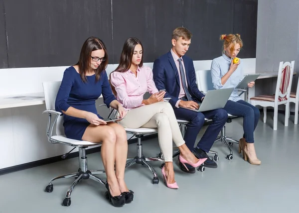 Group of office workers working on laptops sitting on chairs — Stock Photo, Image