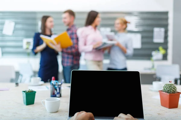 Laptop van de eerste persoon op de achtergrond van een groep van kantoorpersoneel — Stockfoto