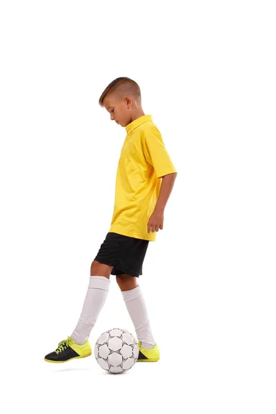 Deportivo lindo colegial pateando pelota de fútbol aislado sobre un fondo blanco. Concepto de ropa deportiva . —  Fotos de Stock