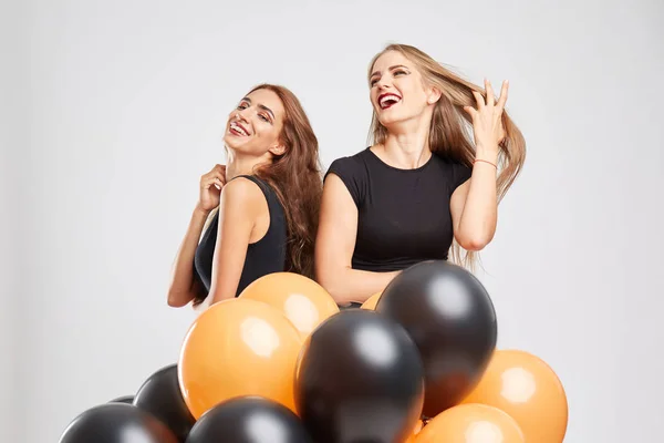Positieve en mooie meisjes met kleurrijke ballonnen op een grijze achtergrond. Halloween vieren concept. — Stockfoto
