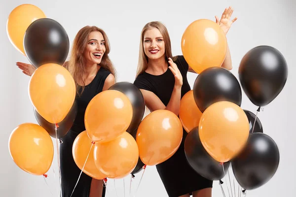 Gelukkig vriendinnen met lucht-verjaardagsballons vliegen op een lichte achtergrond. Viering concept. — Stockfoto