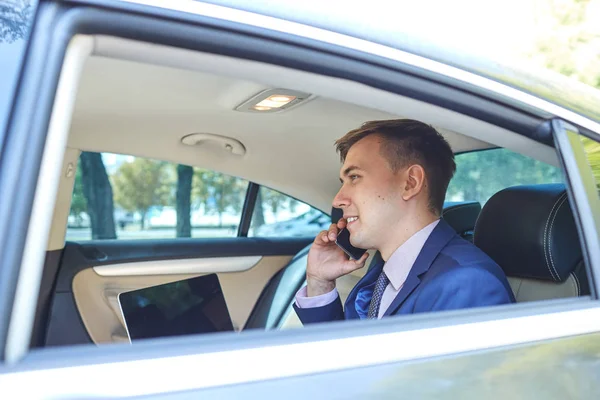 Biznesmen w swoim samochodzie z laptopa rozmawiać przez telefon — Zdjęcie stockowe