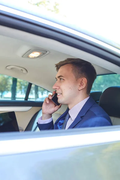 Biznesmen w swoim samochodzie z laptopa rozmawiać przez telefon — Zdjęcie stockowe