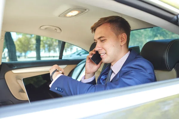 Biznesmen, patrząc na zegar w jego samochodzie z laptopa rozmawiać przez telefon — Zdjęcie stockowe