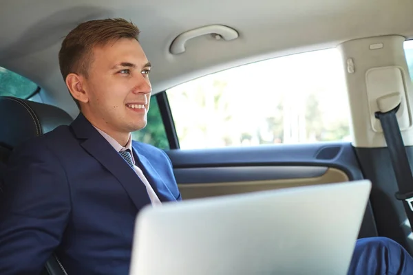 Empresario en el coche trabajando en el portátil — Foto de Stock