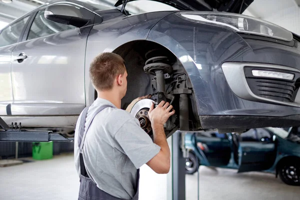 The mechanic repairs the brakes at the machine that broke