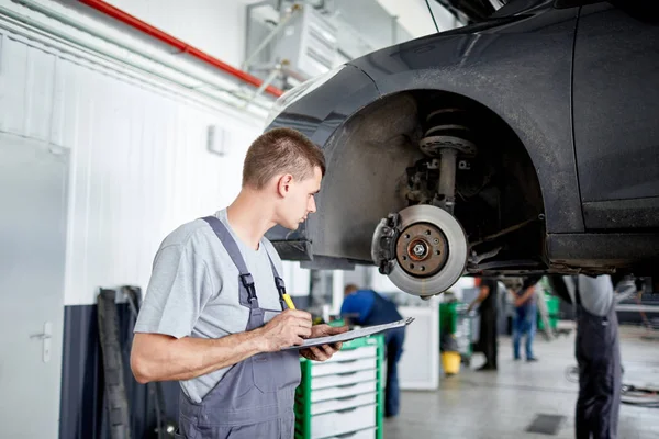 Der Mechaniker beschreibt die Probleme mit den Bremsen und schätzt den Umfang der Arbeit ein — Stockfoto