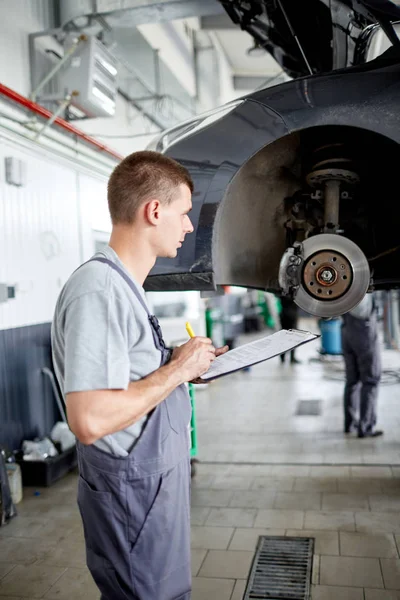 Der Mechaniker beschreibt die Probleme mit den Bremsen und schätzt den Umfang der Arbeit ein — Stockfoto