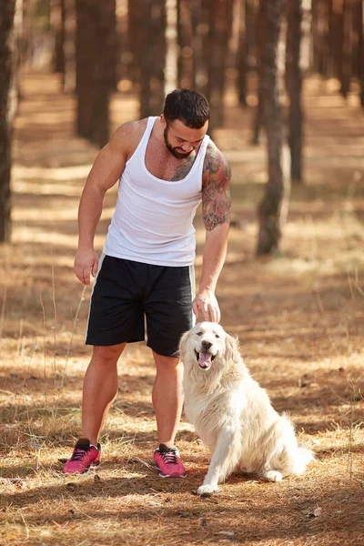 Ormanda açık yürüyen labrador köpek ile güçlü esmer adam.
