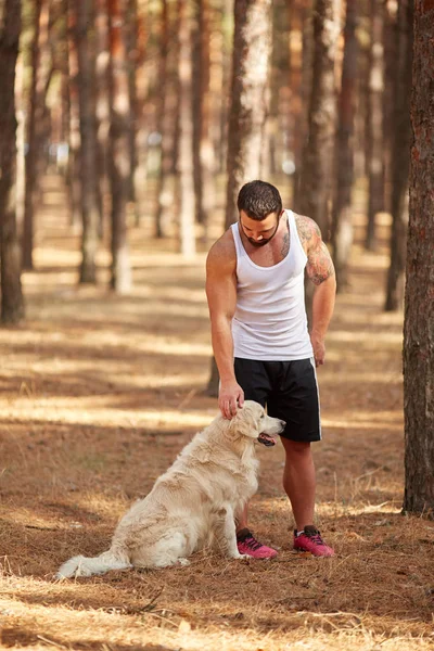 Ormanda açık yürüyen labrador köpek ile güçlü esmer adam.