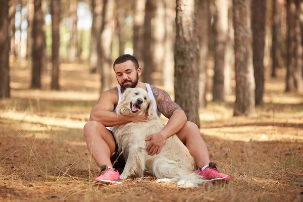 Ormanda açık yürüyen labrador köpek ile güçlü esmer adam.