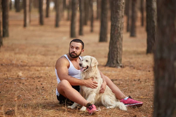Ormanda açık yürüyen labrador köpek ile güçlü esmer adam.