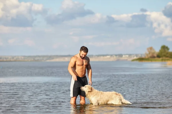 Bir adam bir köpek su ile oynuyor