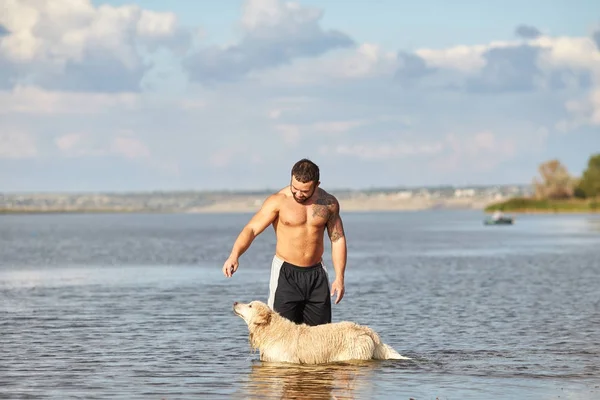 Bir adam bir köpek su ile oynuyor