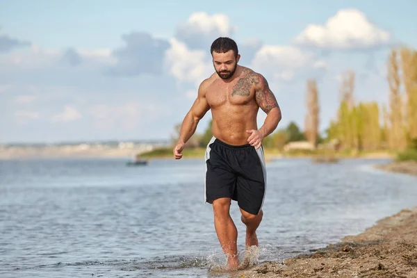 Ein junger Mann joggt am Strand des Südbug River entlang — Stockfoto