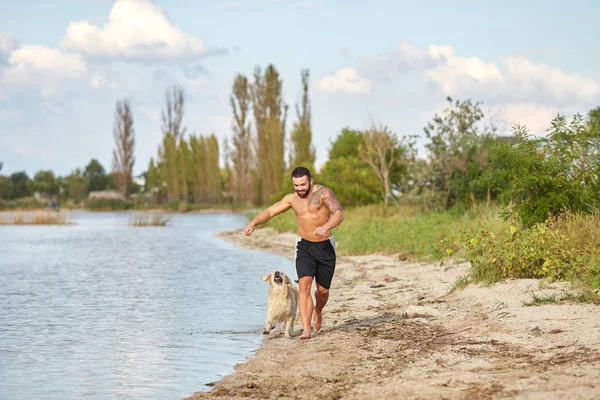 A man runs on the beach with his dog