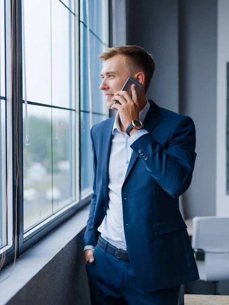 Arka plan bulanık bir telefonda konuşurken mutlu iş Yöneticisi. Teknoloji kavramı.