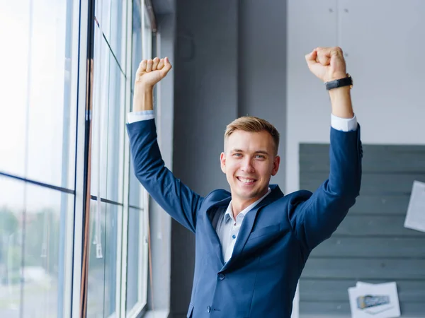 Un hombre de negocios sonriente animando el fondo de la oficina. Feliz oficinista. Concepto de éxito empresarial . —  Fotos de Stock