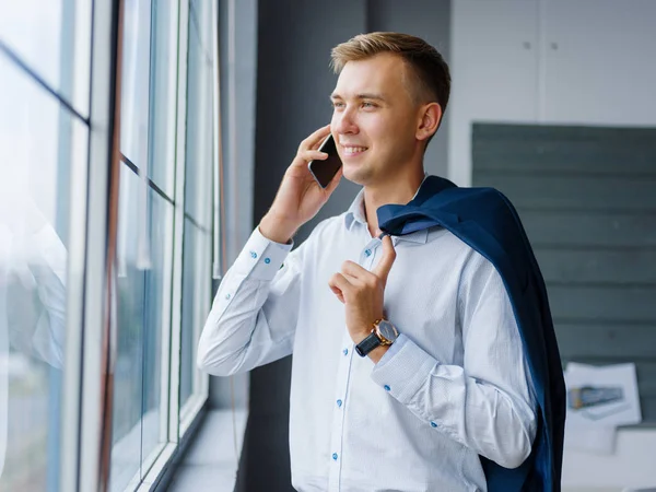 El hombre sonriente de la oficina llamando a un teléfono móvil en un fondo borroso. Concepto de trabajo en red. Copiar espacio . —  Fotos de Stock