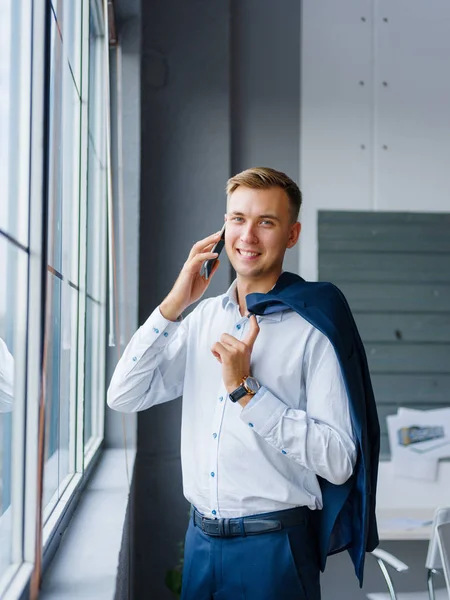 Gülümseyen office adam bir cep telefonu üzerinde arka plan bulanık arıyor. Ağ kavramı. Kopya alanı.