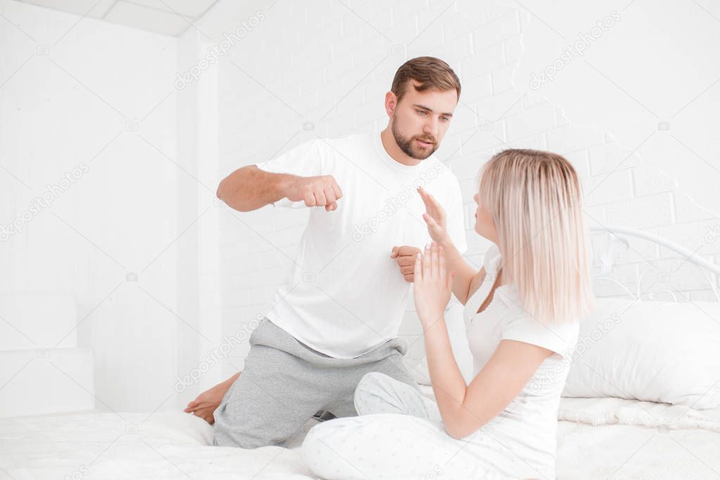 A man wants to hit a girl in bed on a white background