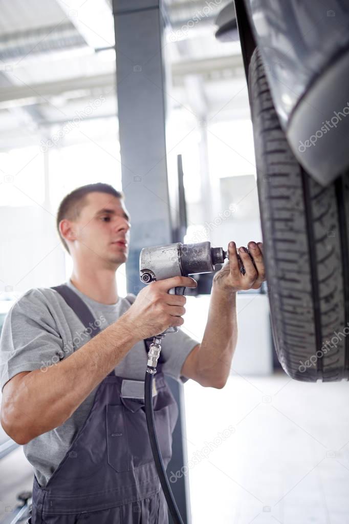 The mechanic twists the wheels of the car on the lift