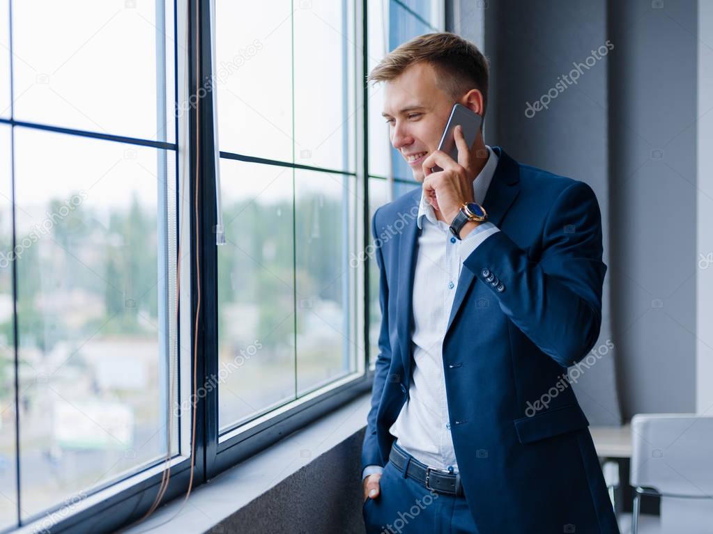 Executive businessman talking on a phone on the office background. Communication concept. Copy space.