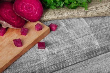 Bir görüntü yukarıdan bir bileşimi bütün ve dilimlenmiş beetroots ve yeşil maydanoz bir hafif kumaş ve ahşap arka plan. Taze ot ve Pancar Salatalar veya bir kesme tahtası üzerinde smoothies için.