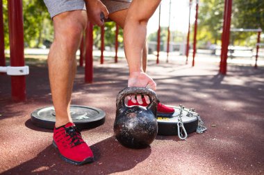 güçlü delikanlı ile seksi vücut egzersizleri kendi ayakları üzerinde yapıyor. adam parkta ayaklarıyla ağırlık kaldırıyor.