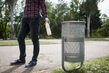 Bir kağıt bardak yeşil park dışında sol alt kapak üzerinde odaklanın. Çim güneşli Park, plastik şişe bulanıklık yeşil doğa arka plan ile yeşil Park'ta çöp yığını.