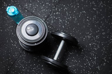 Üstten Görünüm mavi bir şişe su ve iki ağır metal halter için çiftler halinde güreşçiler, vücut geliştiriciler, spor oyuncular, rutinleri egzersiz programı içinde karanlık bir arka plan bulanık üzerinde spor salonları makineleri.