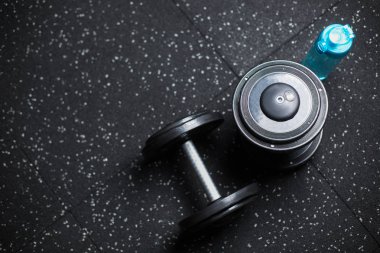 Üstten Görünüm mavi bir şişe su ve iki ağır metal halter için çiftler halinde güreşçiler, vücut geliştiriciler, spor oyuncular, rutinleri egzersiz programı içinde karanlık bir arka plan bulanık üzerinde spor salonları makineleri.