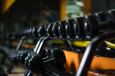 Demir dambıl, ağırlık kaldırma, spor salonu, ağırlık çalışması, egzersiz programı, artan gücü ve kaslar üzerinde karanlık bir arka plan bulanık boyutunu rutinleri için donatım.