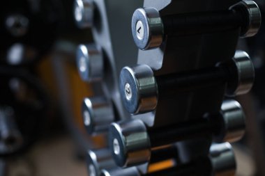 Küçük metal dumbbells bir bulanık spor salonu zemin üzerine sahibinin yakın çekim bir resim. Mesleki eğitim ve halter için donatım. Sağlıklı ve aktif egzersiz ağırlık kavramı ile.