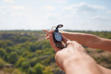 Dağ yolundan günbatımı gökyüzüne, pusula ile turistler'ın el. Küçük gösterilen el görünümünü yakın çekim yuvarlak kamerayla gizli adam pusula. Bakış açısı vurdu.
