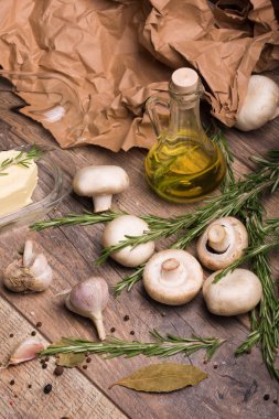 büyük bir parça tereyağı şeffaf bir kutu, bazı mantar, biberiye ve bir şişe zeytinyağı ahşap arka plan üzerinde bileşimi. 