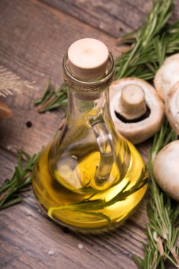 Kahverengi ahşap arka plan şeffaf sürahi ayçiçek yağı tam bir görüntü yukarıdan. Birkaç doğal ve organik mantar masanın üzerine biberiye dalı ile.