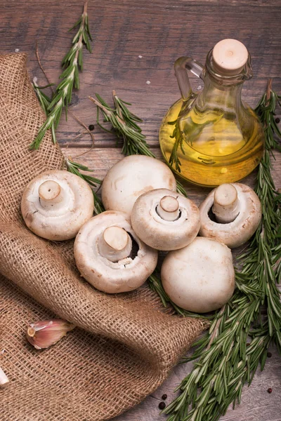 Ahşap arka plan şeffaf şişe zeytinyağı, sarımsak ve Baharatlı yeşil biberiye dolu bir manzara yukarıdan. Doğal ve organik petrol ormandaki bir çanta ve bir masa yığını.