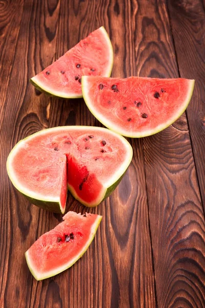 Hafif kahverengi ahşap arka plan üzerinde kesme bir karpuz. Güzel karpuz parçalar bileşimi. Bir tabloda en iyi görünüm büyük karpuz Berry. Vegan milkshakes hazırlanması.