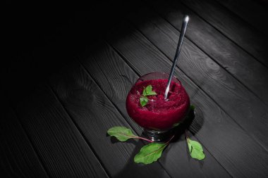 Büyük bir cam siyah tablo arka plan üzerine rendelenmiş pancar dolu. Sağlıklı sebze bordo renkli yemek yeşil pancar yaprakları ile çevrili bir metal kaşıkla bileşimi. Kopya alanı.