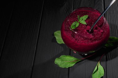 Büyük bir cam siyah tablo arka plan üzerine rendelenmiş pancar dolu. Sağlıklı sebze bordo renkli yemek yeşil pancar yaprakları ile çevrili bir metal kaşıkla bileşimi. Kopya alanı.