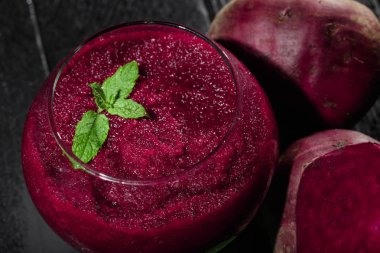 Parlak kırmızı pancar güler yüzlü bir cam siyah tablo arka plan üzerinde bir yakın çekim resim. Sulu beetroots taze salata yaprakları ve yeşil dekoratif nane ile. Detoksifikasyon ve diyet kavramı.