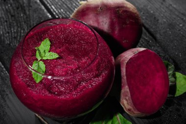 Parlak kırmızı pancar güler yüzlü bir cam siyah tablo arka plan üzerinde bir yakın çekim resim. Sulu beetroots taze salata yaprakları ve yeşil dekoratif nane ile. Detoksifikasyon ve diyet kavramı.