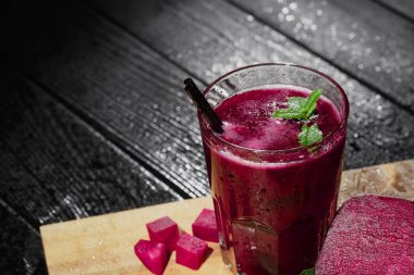 Fantastik kalın kırmızı suyu yanan ahşap arka plan üzerinde geniş bir bardak. Dekoratif nane ile pancar güler yüzlü bırakır. Koyu pembe pancar küpleri besleyici bir salata için kesti. Serinletici içecekler.